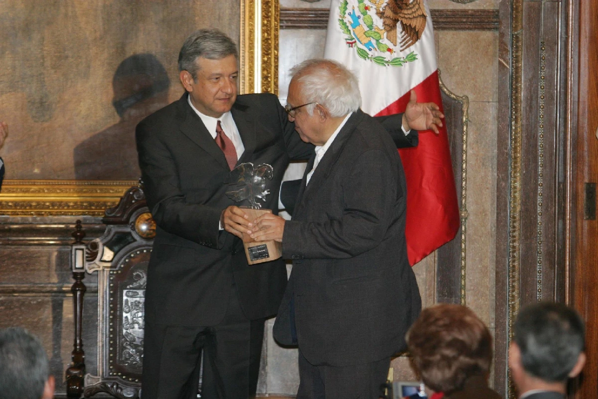 AMLO entregándole una estatua a carlos monsiváis mientras le da un abrazo 